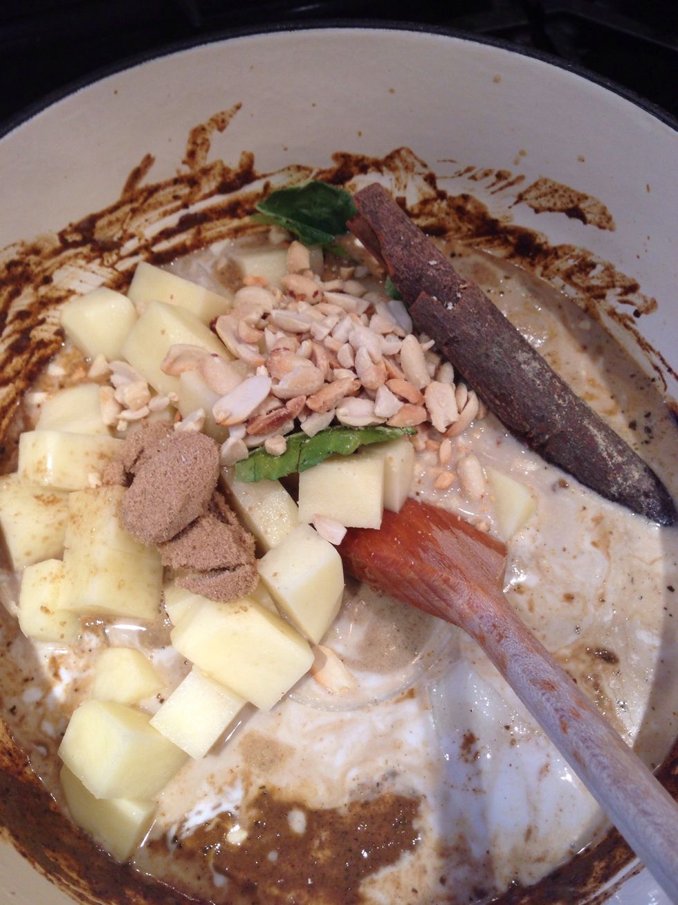 Add the rest of the coconut milk and water. Then add the potatoes, onion, kafir leaves, cinnamon, tamarind, fish sauce and most of the peanuts and sugar