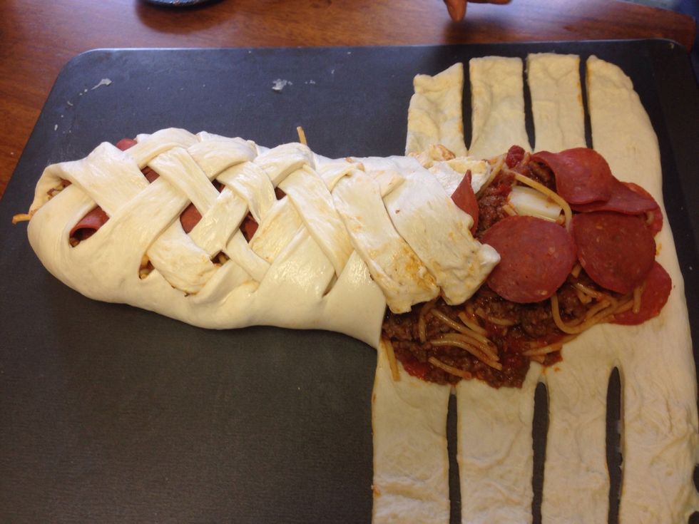 Add the spaghetti and cheese (and pepperoni) to the center of the flattened loaf and then cut 1&1/2' strips along both sides. Begin braiding the bread by folding one side over the other.