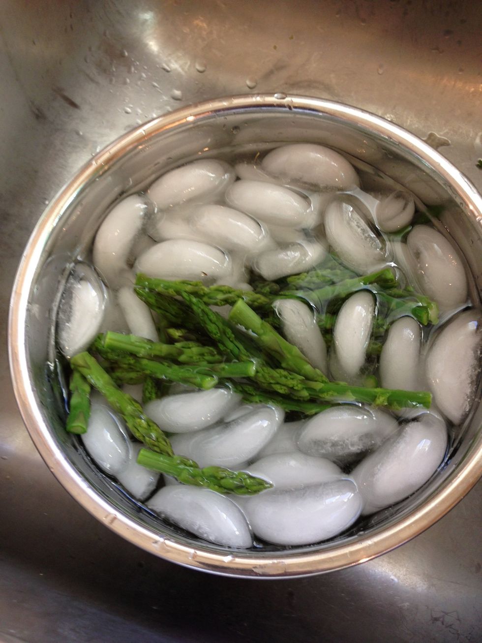 Add the spears in the ice bath to shock and stop the cooking. This obviously stops the spears from cooking, but also keeps the bright green color.