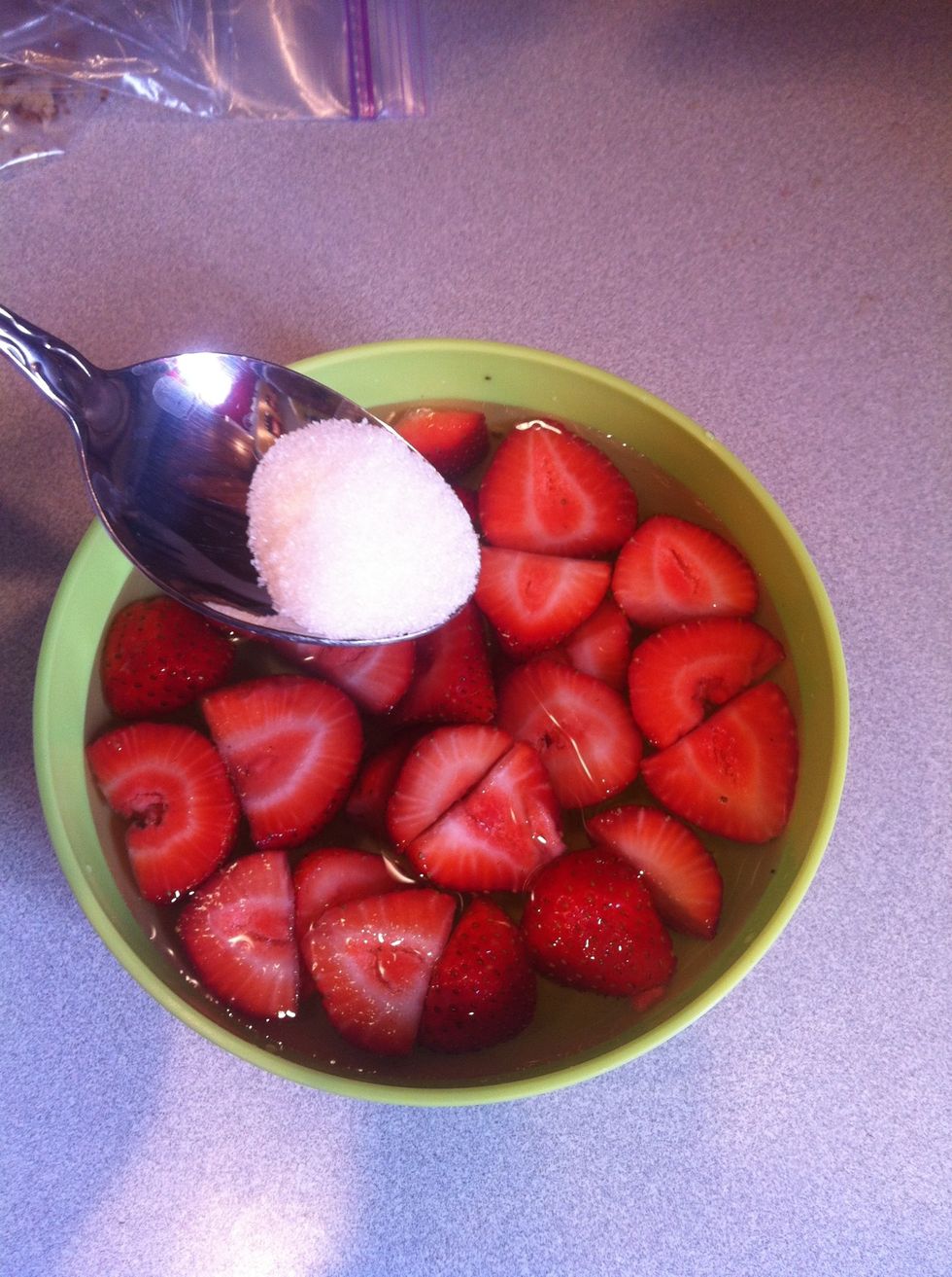 Add the sugar to the bowl of water and strawberries.