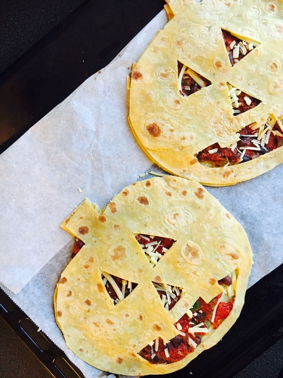 Add the tomato-mix on top of the cheese. Cut out 'Jack-O-Lantern- faces' for the other tortilla/ top 'lid' and put on top.