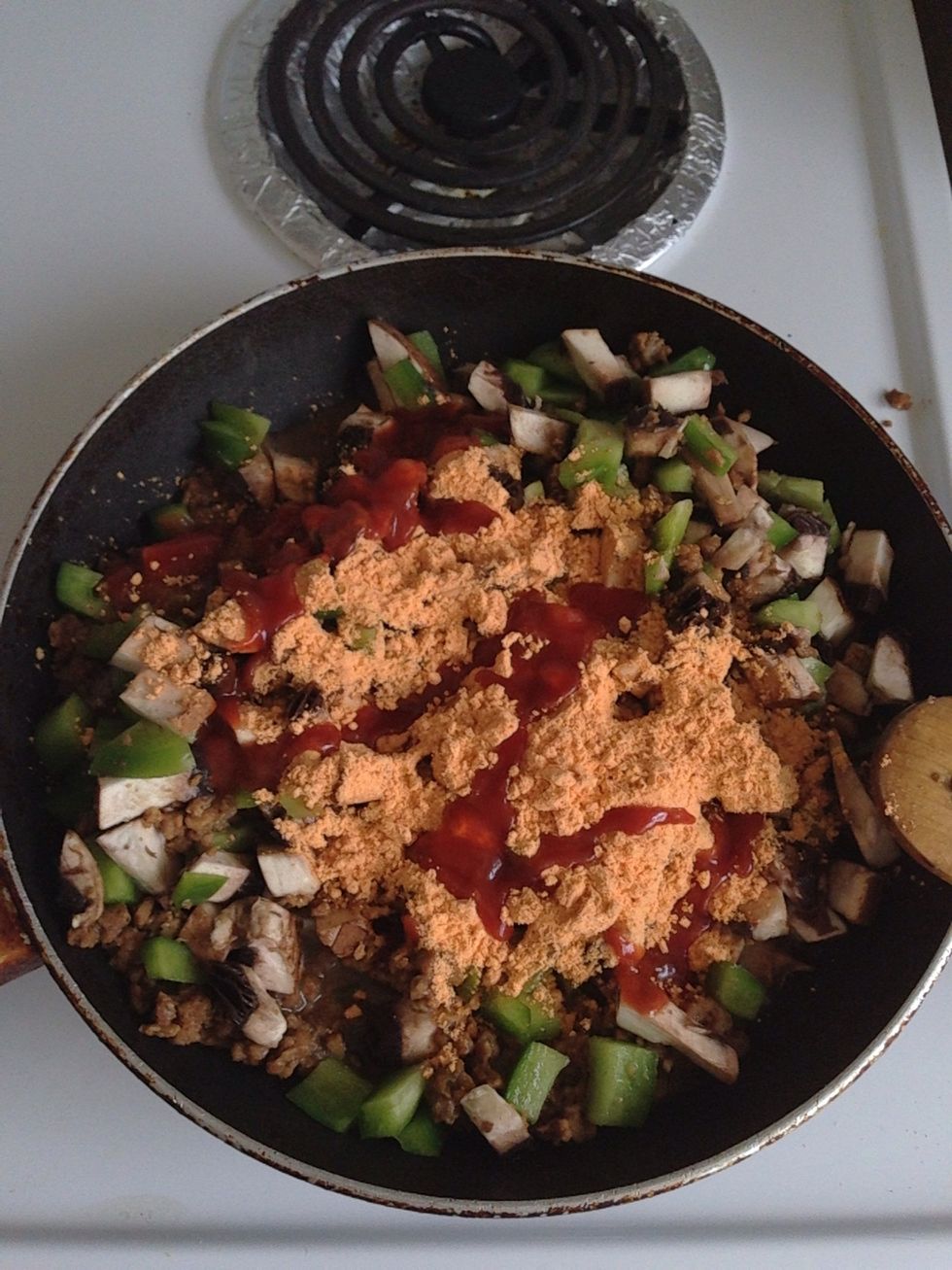 Add the veggies, seasoning, and a little bit of the red sauce along with the water to the veggie ground. Stir until blended and let simmer until the water reduces and the veggies soften just a little.