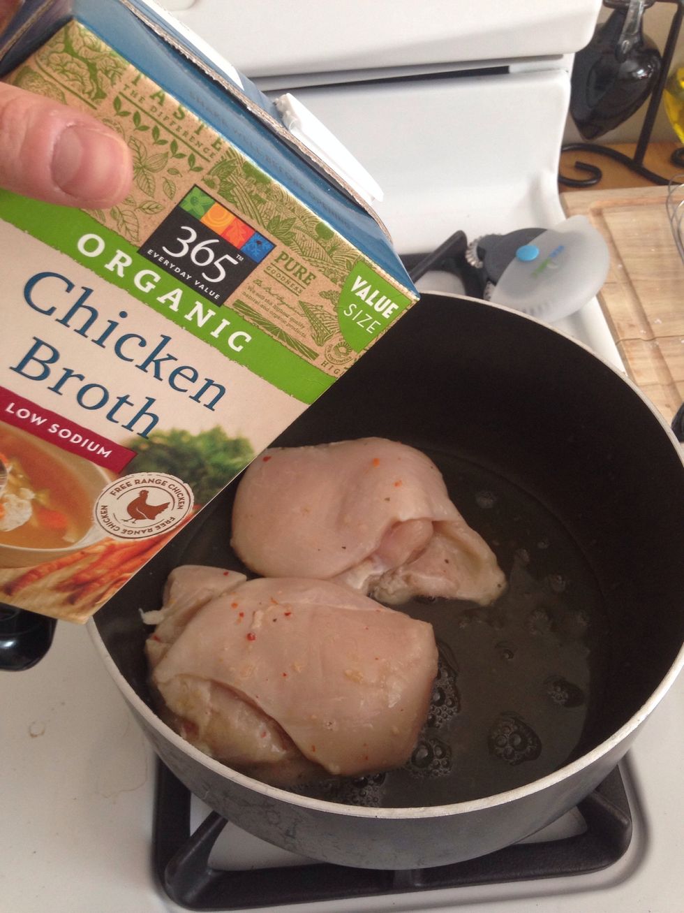 Add three chicken breast to a pan. Cover the middle chicken with chicken broth.