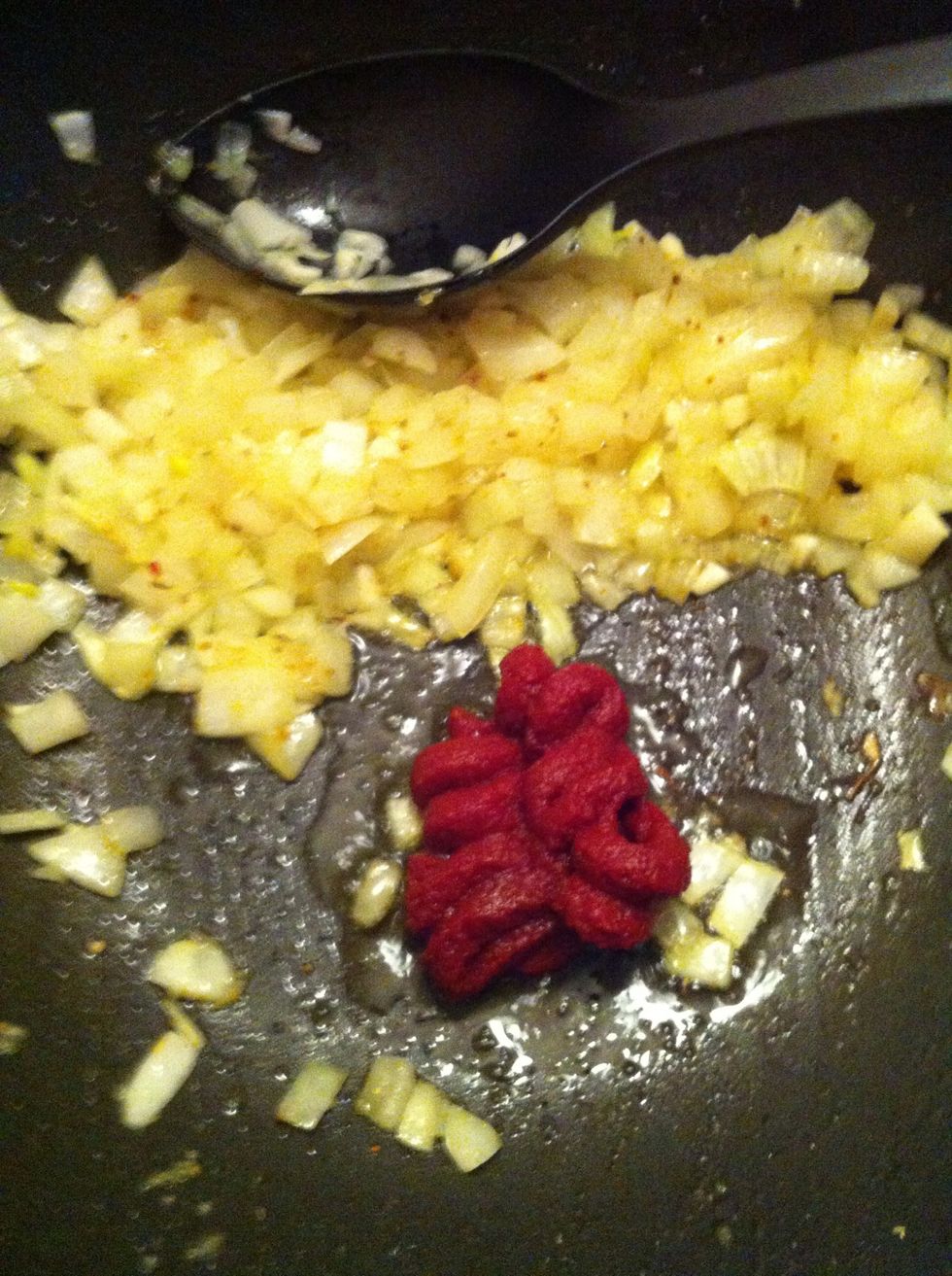 Add tomato paste and let the paste fry. Mix it in with the onions.