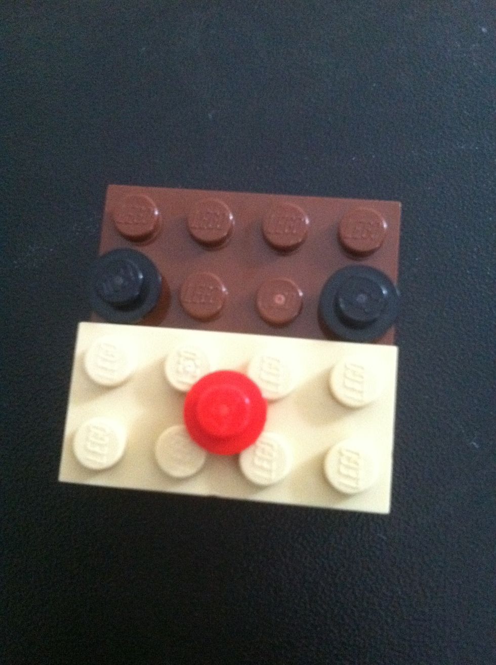 Add two black 1 holed pieces for eyes and one red in the middle for the mouth