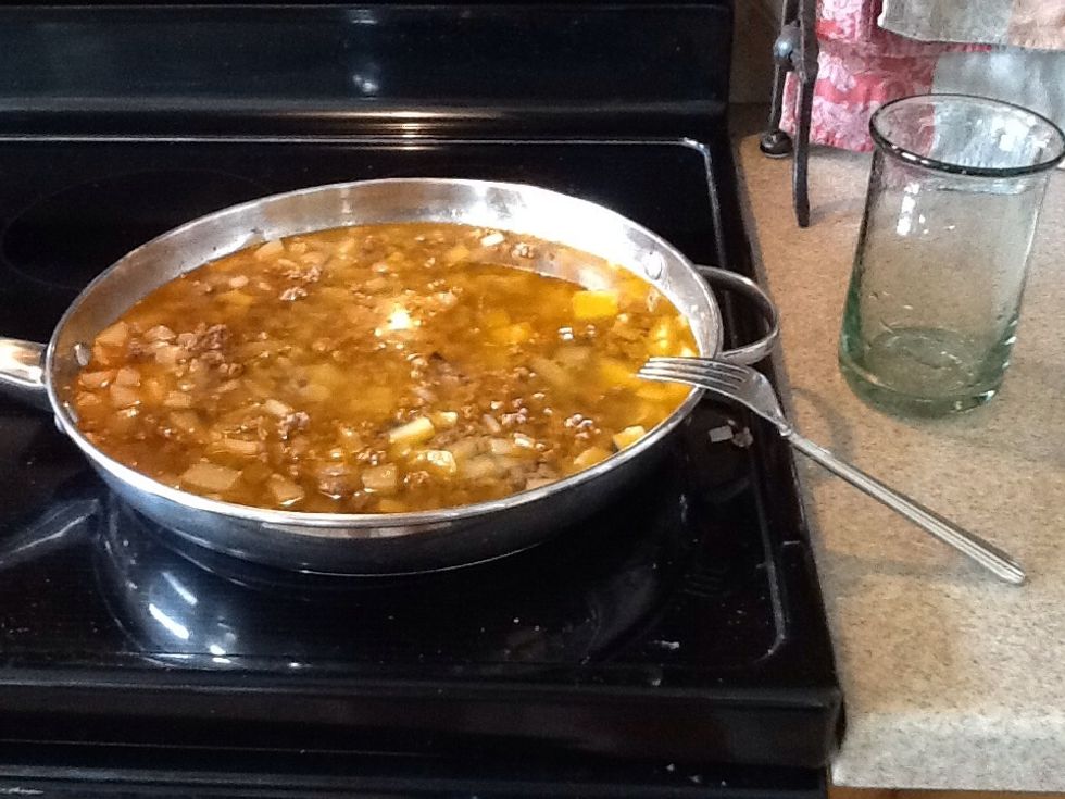 Add water to the pan. You will need to cover all of the meat, onions, and potatoes. See the nice color the chili powder makes this dish?