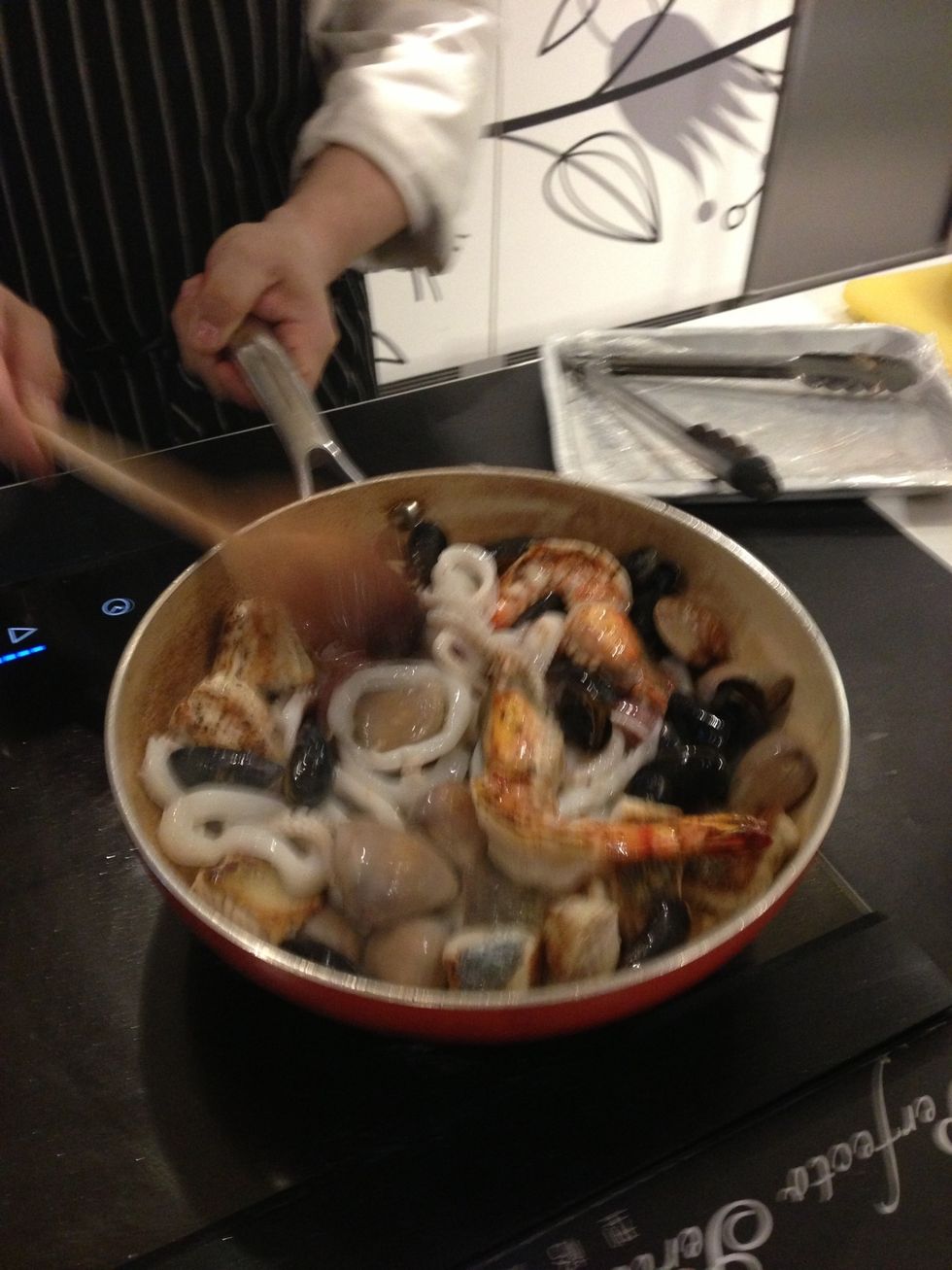 Add white wine and cook until no wine smell. Add a ladle's worth of soup base. Add saffron shreds and tomato sauce. Turn to medium heat