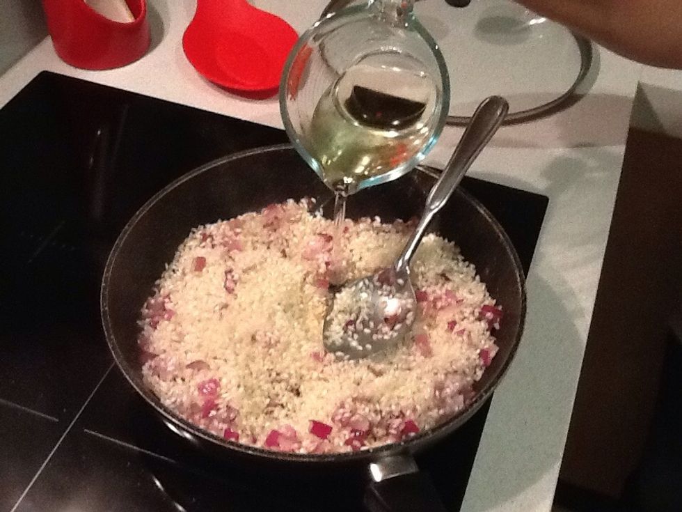 Add wine to the rice. Stir until absorbed.