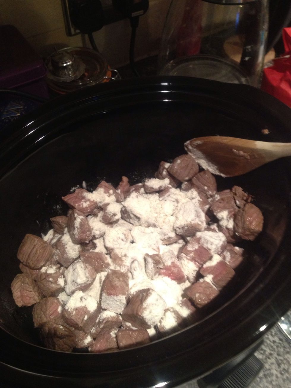 Add your meat, onions and garlic to the slow cooker. Add the flour and mix. The slow cooker should be off at this point.