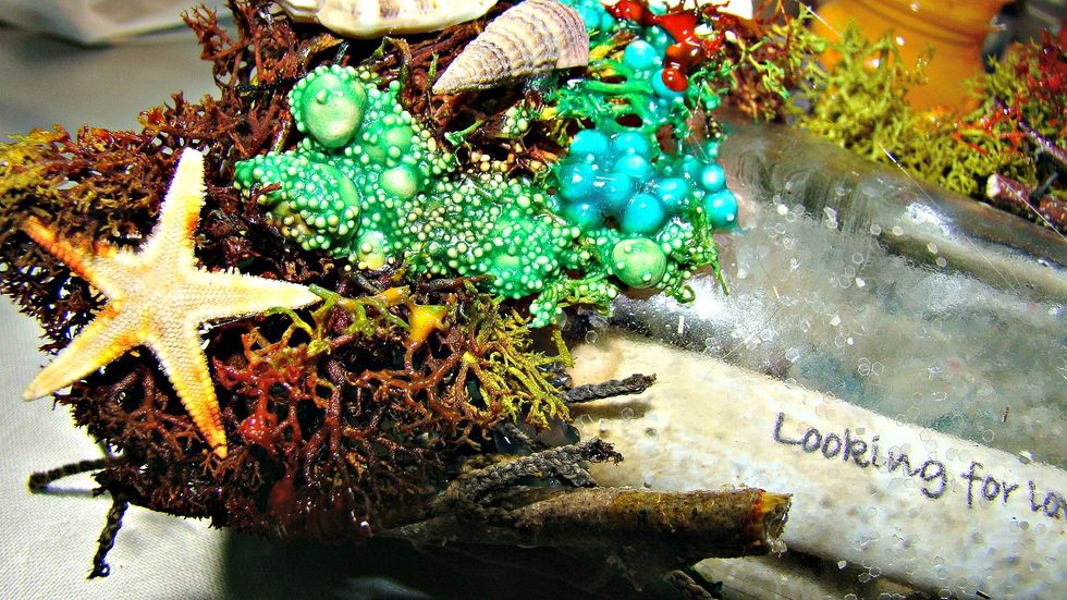 Add your moss, wood pieces, shells, art stones and whatever other embellies you would like to the outside of the bottle.