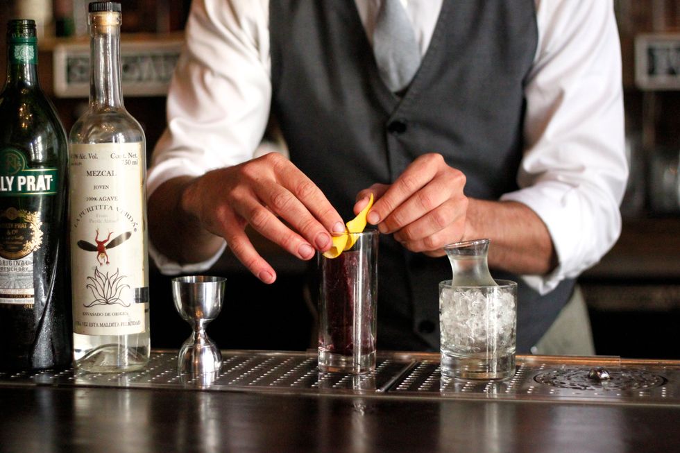 Add your port ice cube (port, white rum, mole bitters, and simple syrup heated in a saucepan. Light it on fire, reduce by half. Chill, add to tall ice cube mold) and lemon twist to a tall glass