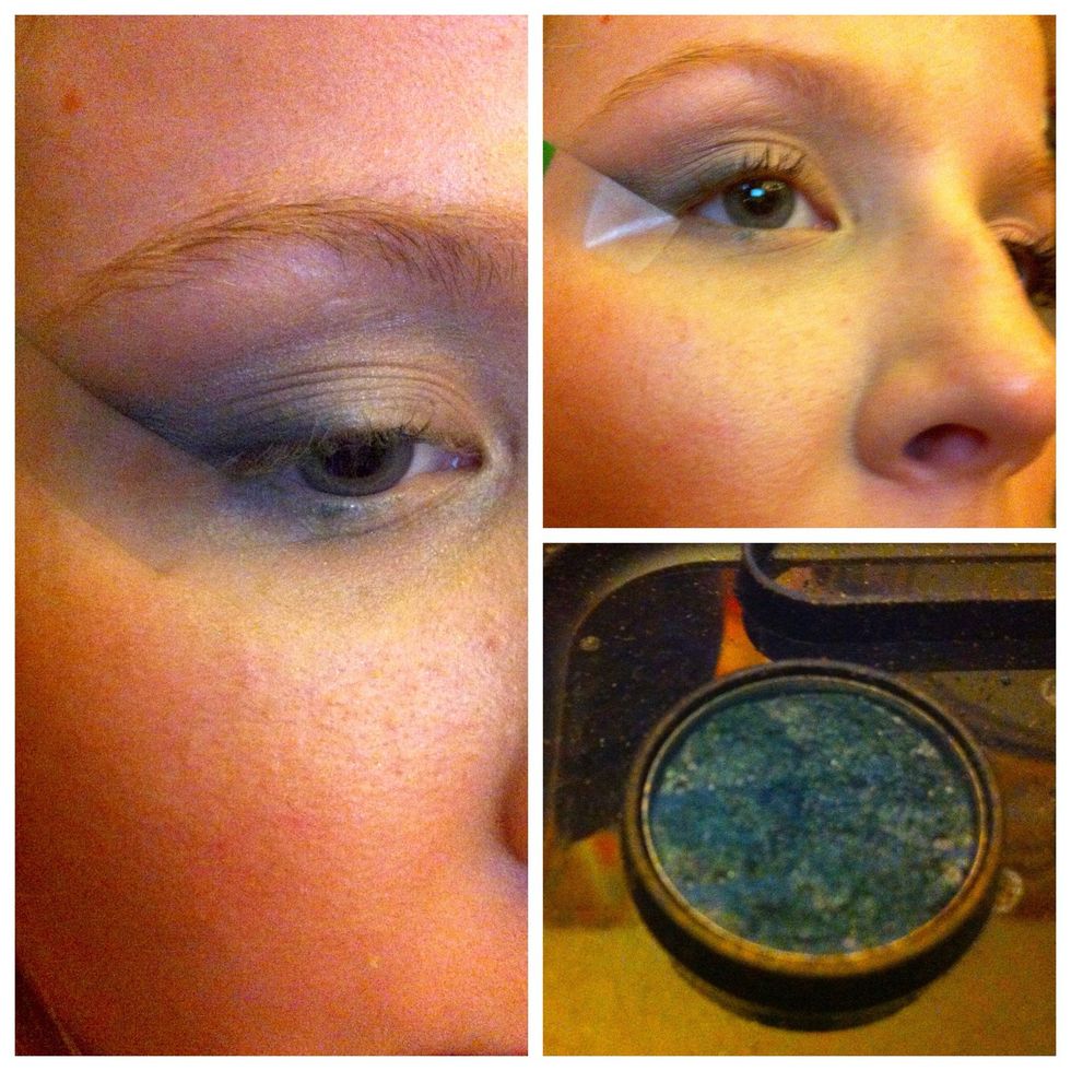 Adding depth, blend a deeper shade that still has bright color-I picked a dark royal blue-along the tape, tapering up to the brow to begin the cateye shape, and along the outer edge of the lash line.