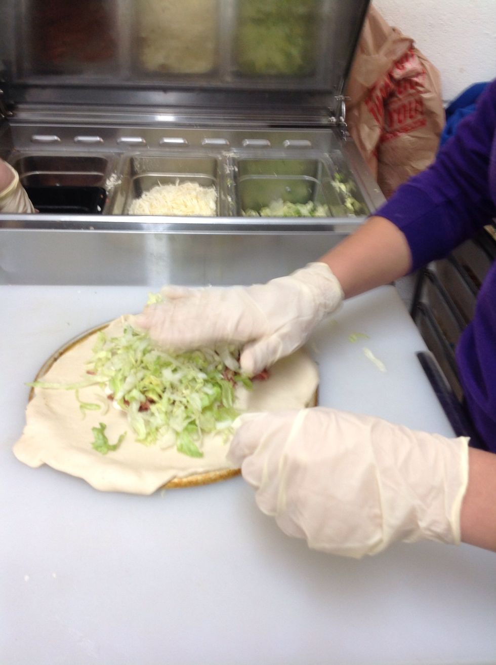 Adding lettuce to the bacon on the calzone