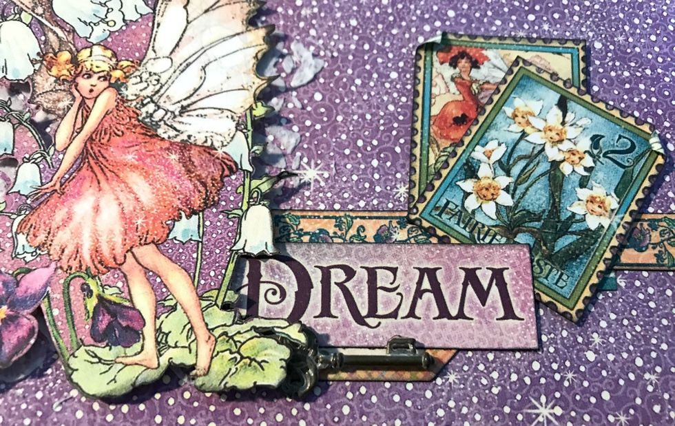 Adhere a bunch of flowers to the right of the fairie's wing. Adhere a shabby chic key underneath the Dream word.