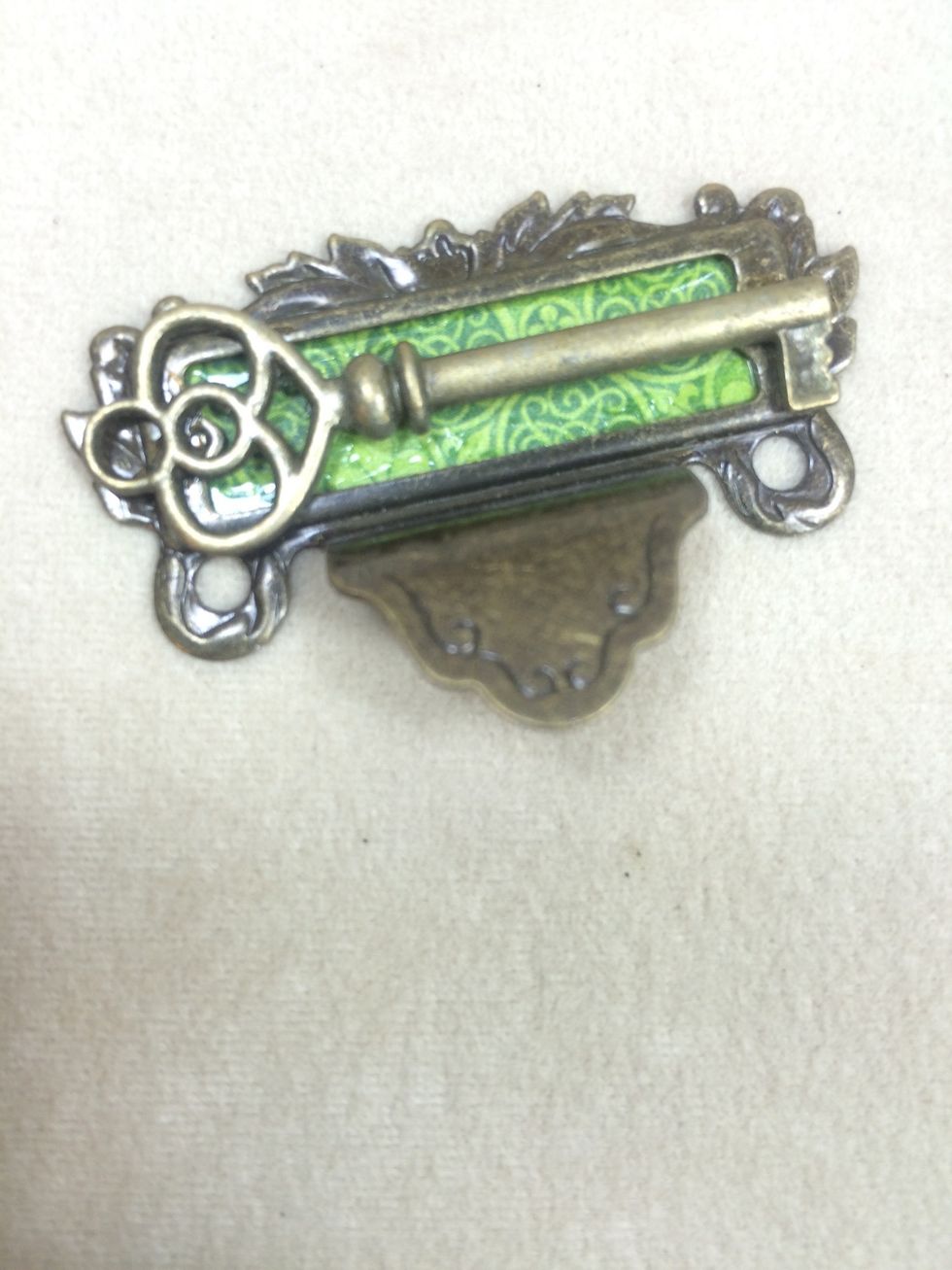 Adhere a small piece of green paper to the back of a metal label pull, then adhere a metal key with strong metal glue.