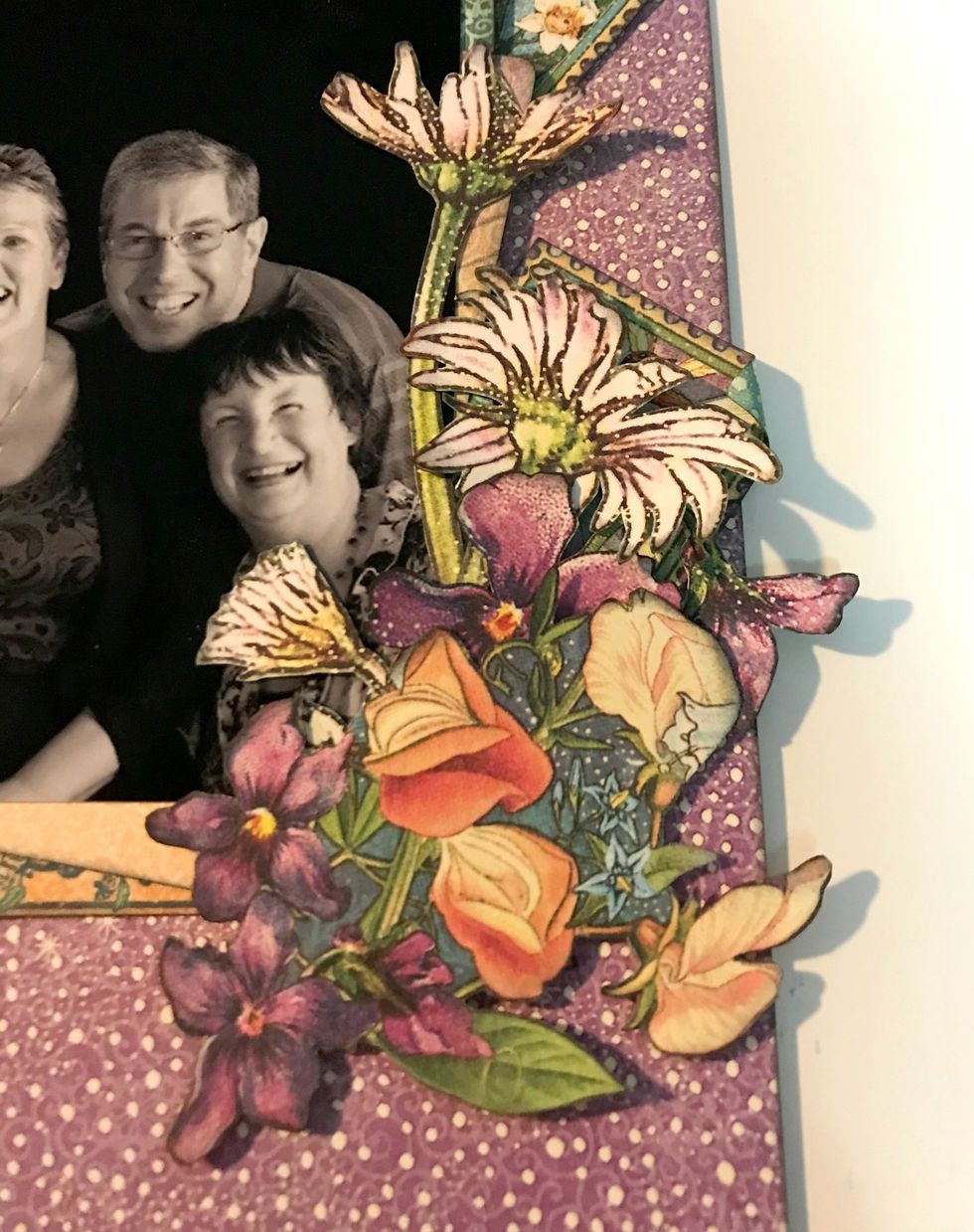 Adhere a stamp underneath the daisy bunch. Roll one corner down on stamp. Adhere the pansy bunch to the right of the daisies. Adhere a flower bunch at the bottom of the daisy & pansy bunches.