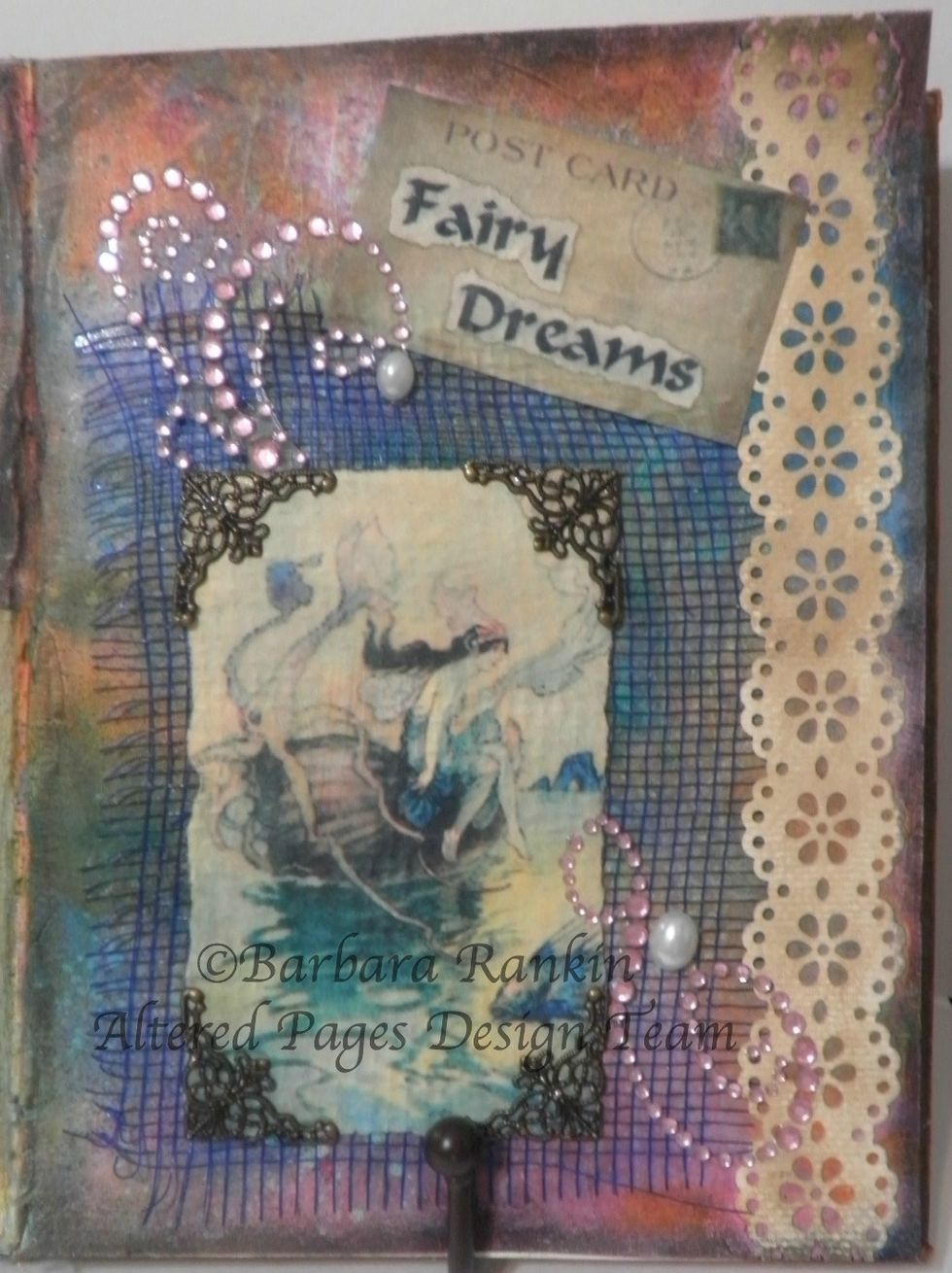 Adhere scrap of blue open weave fabric and torn fairy image to page with with DecoArt Matte Medium. Tear around the words "Fairy Dreams" and adhere to Post Card image with DecoArt Matte Medium.