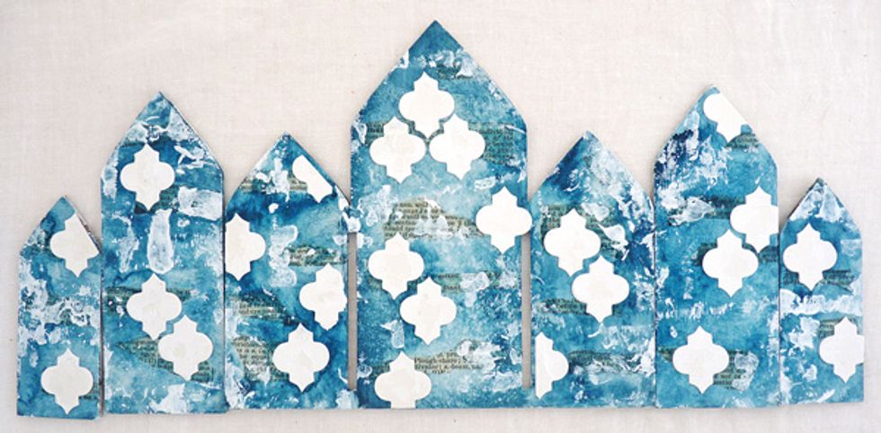 Adhere small die-cuts and brayer white paint lightly over the whole background. Dry. Note I am doing the same with the four small side panels as I am to the frame background.
