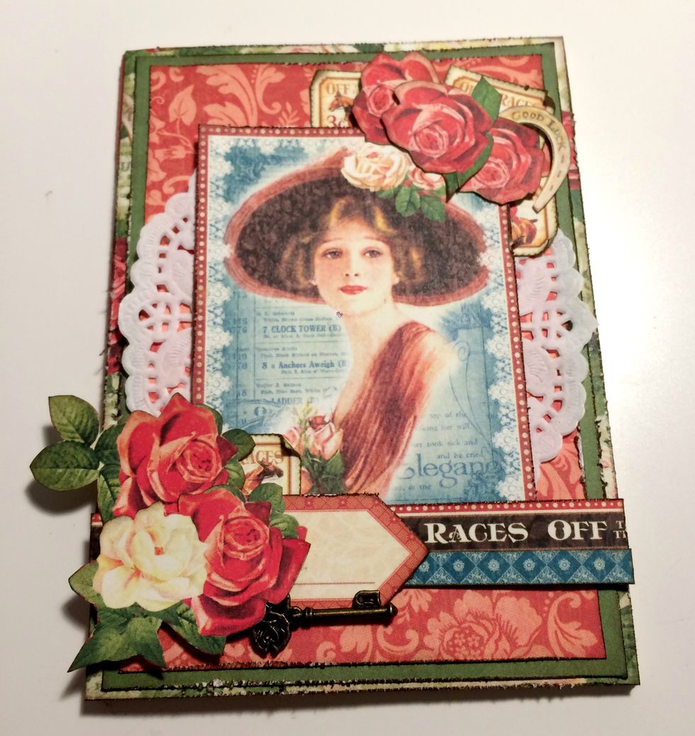 Adhere the arrow 3/4" from the left of the rose paper. Foam square the rest of the roses in the bottom left hand corner as desired. Once the roses are adhered, add the ornate key underneath the arrow.