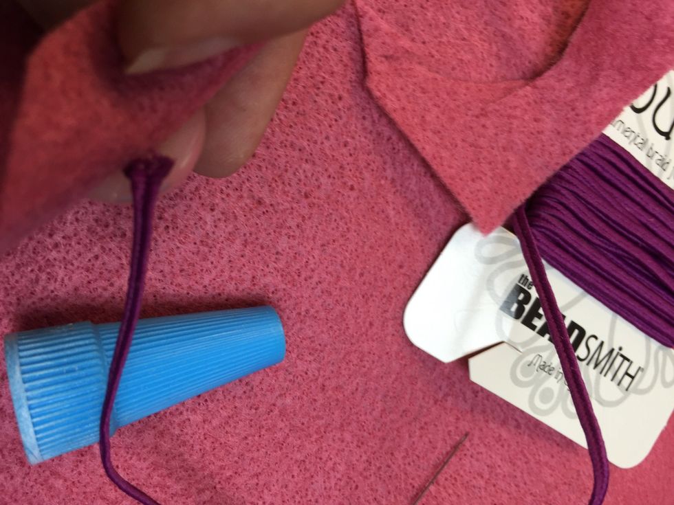 Adhere the bead to the felt and hide the first piece of cording behind it