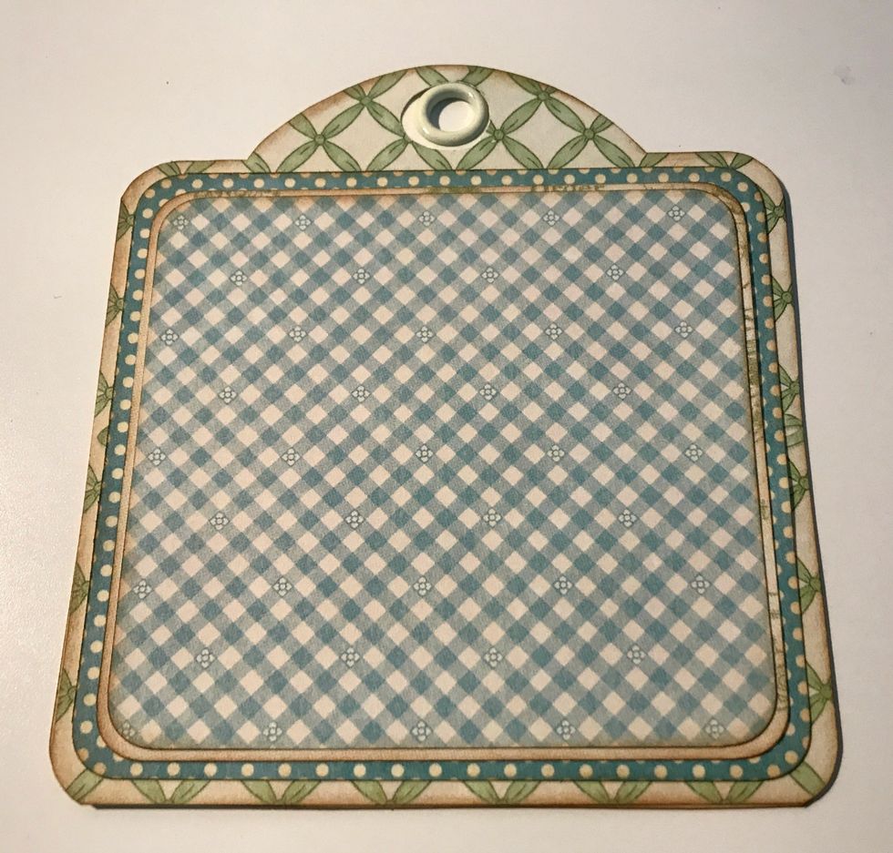 Adhere the blue polka paper to the green lattice tag. Adhere the green word paper to the blue polka dot paper. Adhere the blue checkered paper to the green word paper.