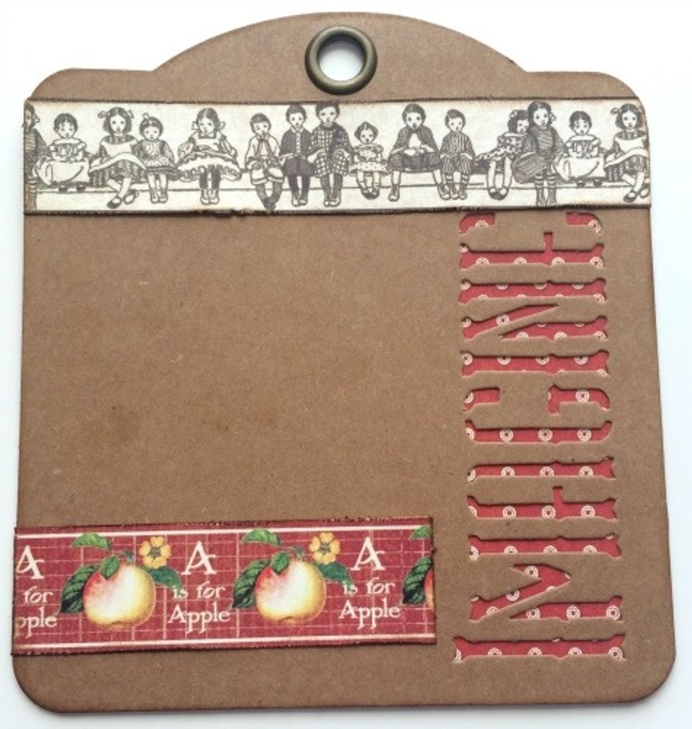 Adhere the children border to the top of the tag. Make sure it sits slightly underneath the eyelet. Adhere the apple border 1/4" from the bottom of the tag. Make sure the border is right to the edge.