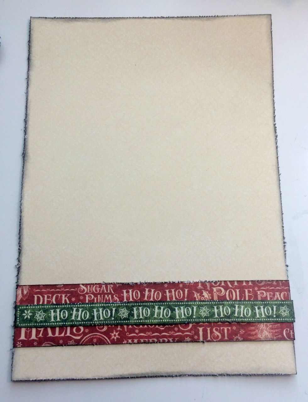 Adhere the Ho Ho Ho border to the middle of the red strip. Adhere the red strip 1/2" from the bottom of the cream patterned paper.