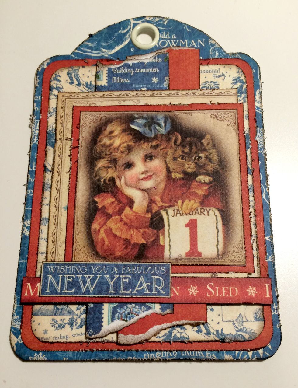 Adhere the mittens border 1 1/2" from the bottom of the tag. Adhere the Wishing you cut apart 3/8" from the left of the tag.