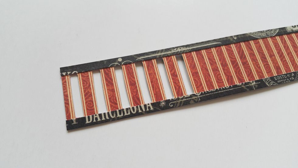 Adhere the narrow strips on the top and bottom of the wider one, cut out alternate strip patterns to make it like a fence, apply ink on edges.