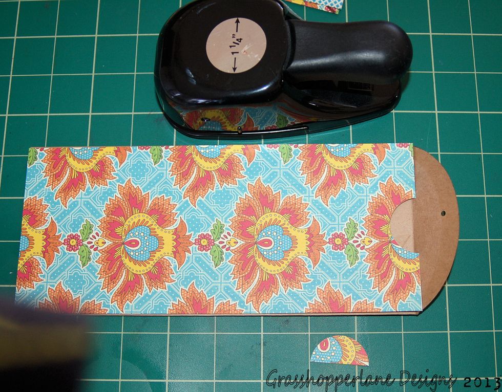 Adhere the paper to the pocket side of the envelope and punch 1/2 of a 1 1/4" hole as shown. This will allow us to pull our photo tab in and out of the pocket easily.