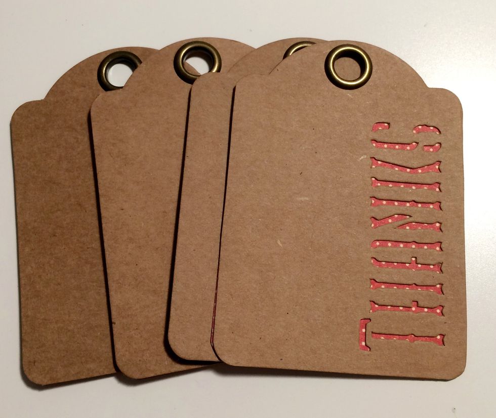 Adhere the red dot side of the cut paper tags to the back of four thanks tags. You'll have the plain red side of the paper showing on the back of the Thanks tag.
