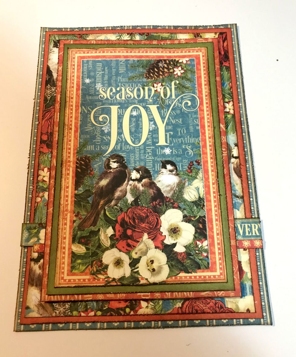 Adhere the Season of Joy card to the green paper. Adhere the green paper to the small red patterned paper. Foam square the red patterned paper to the middle of the floral paper.