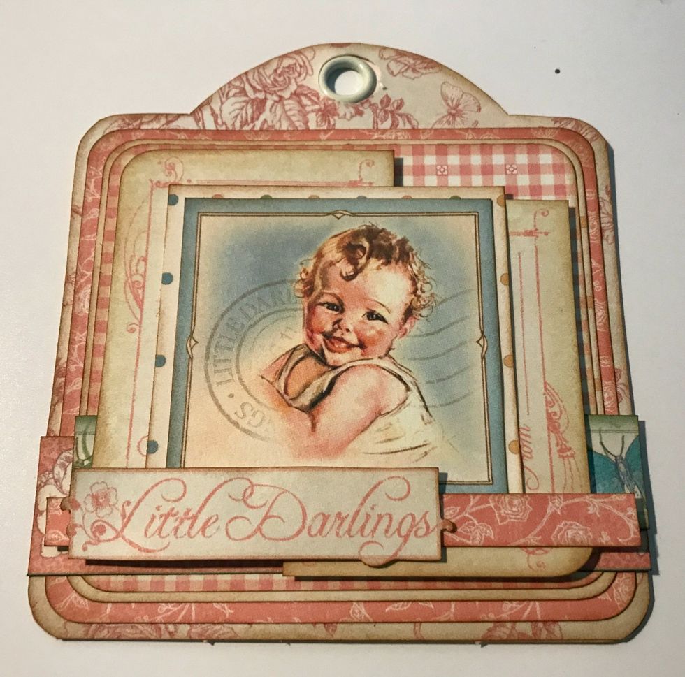 Adhere the skinny pink floral border 5/8" from the bottom of the tag. Foam square the Little Darlings sentiment 3/8" from the left of the tag.
