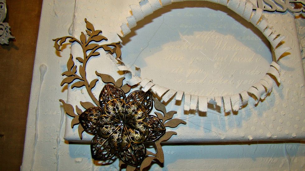 Adhere your metal embellies and cover the entire canvas and metal pieces with a coat of gesso.