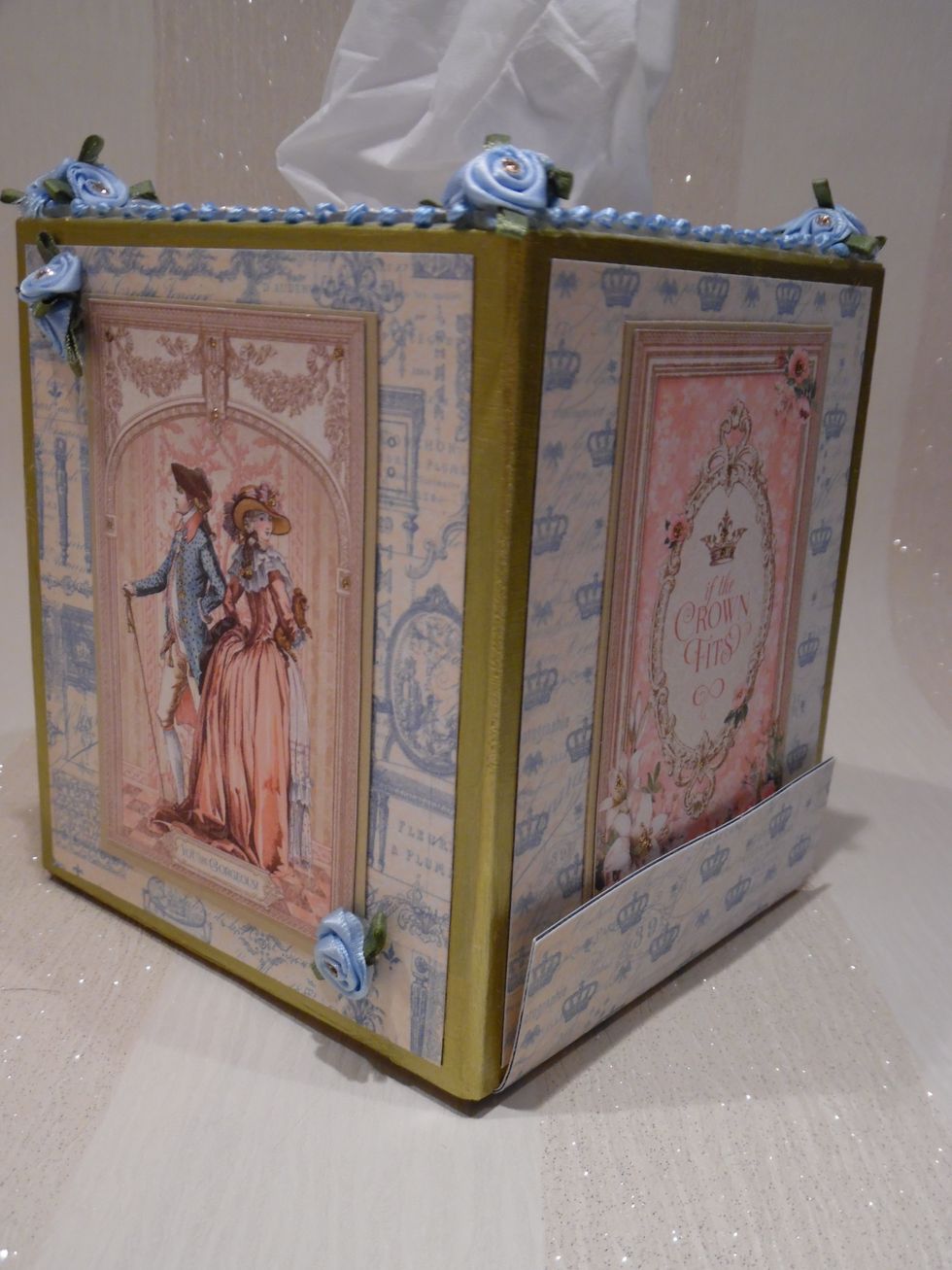 Adorned with Gilded Lily papers. Trimmed with Blue & white braid, blue silk roses and glittered to taste. Base held closed by magnetic strip hidden under decoration. Base covered in self adhesive felt