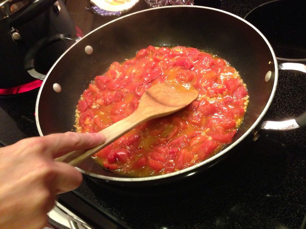 After 10 minutes, the tomatoes will have broken down quite a bit and released some liquid. Use the back of a spoon to gently press on the tomatoes.