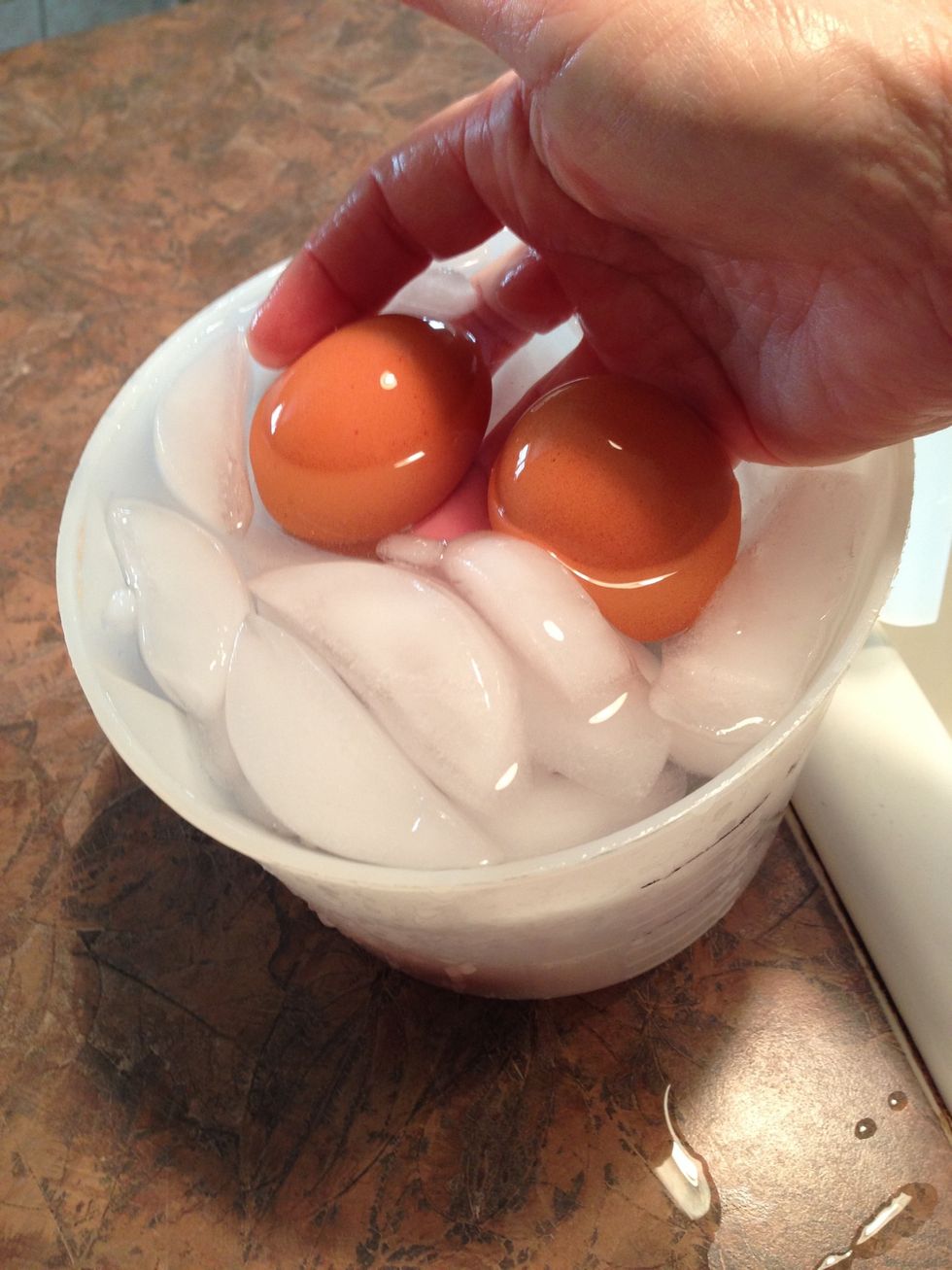 After 15 minutes immediately immerse hot cooked eggs into cold water with ice cubes. This stops the cooking and cools them.