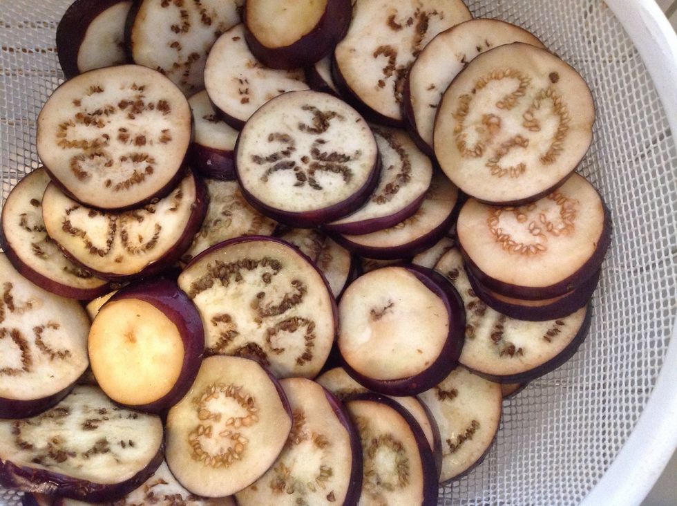 After 30 minutes. Rinse the eggplant in the colander under water. Place the slices in a single layer on paper towels. Cover with paper towels and press to remove excess water from the eggplant slices.
