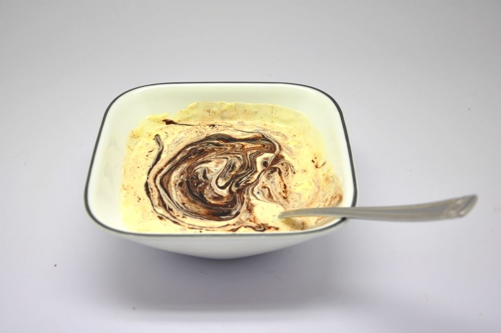 After 5 minutes, using a spoon (cause that's the only thing we're gonna use to decorate), start mixing it. You'll see that all the chocolate has melted and its slightly thicker.