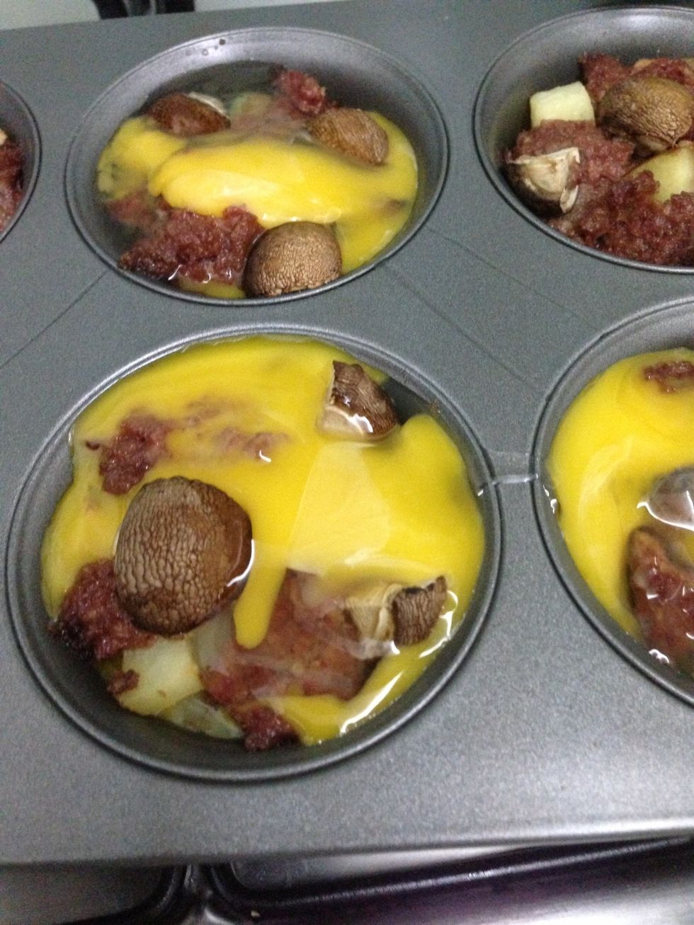 After about 5 mins, take out the muffin tin and crack an egg over. Put the muffin tin back into the oven