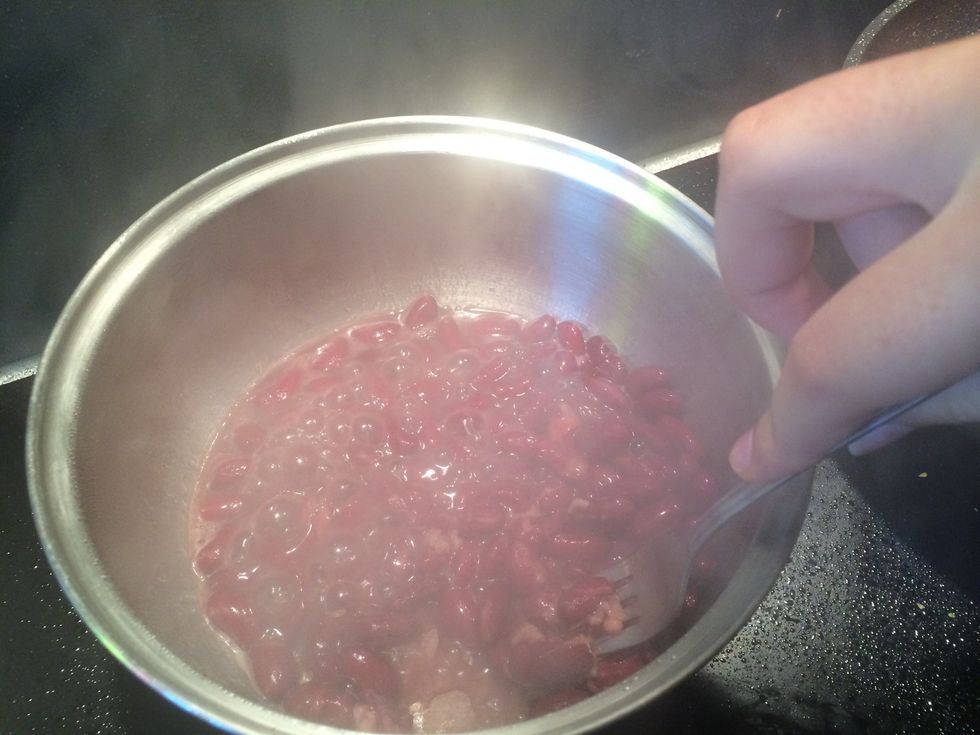 After about a minute, mash the beans with a fork.