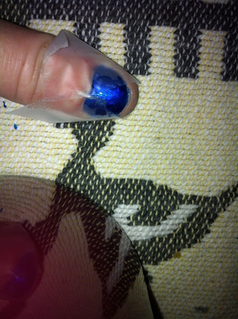 After allowing the polish to dry for 10 minutes,place tape on both sides of finger over existing blue nail polish in a triangle shape