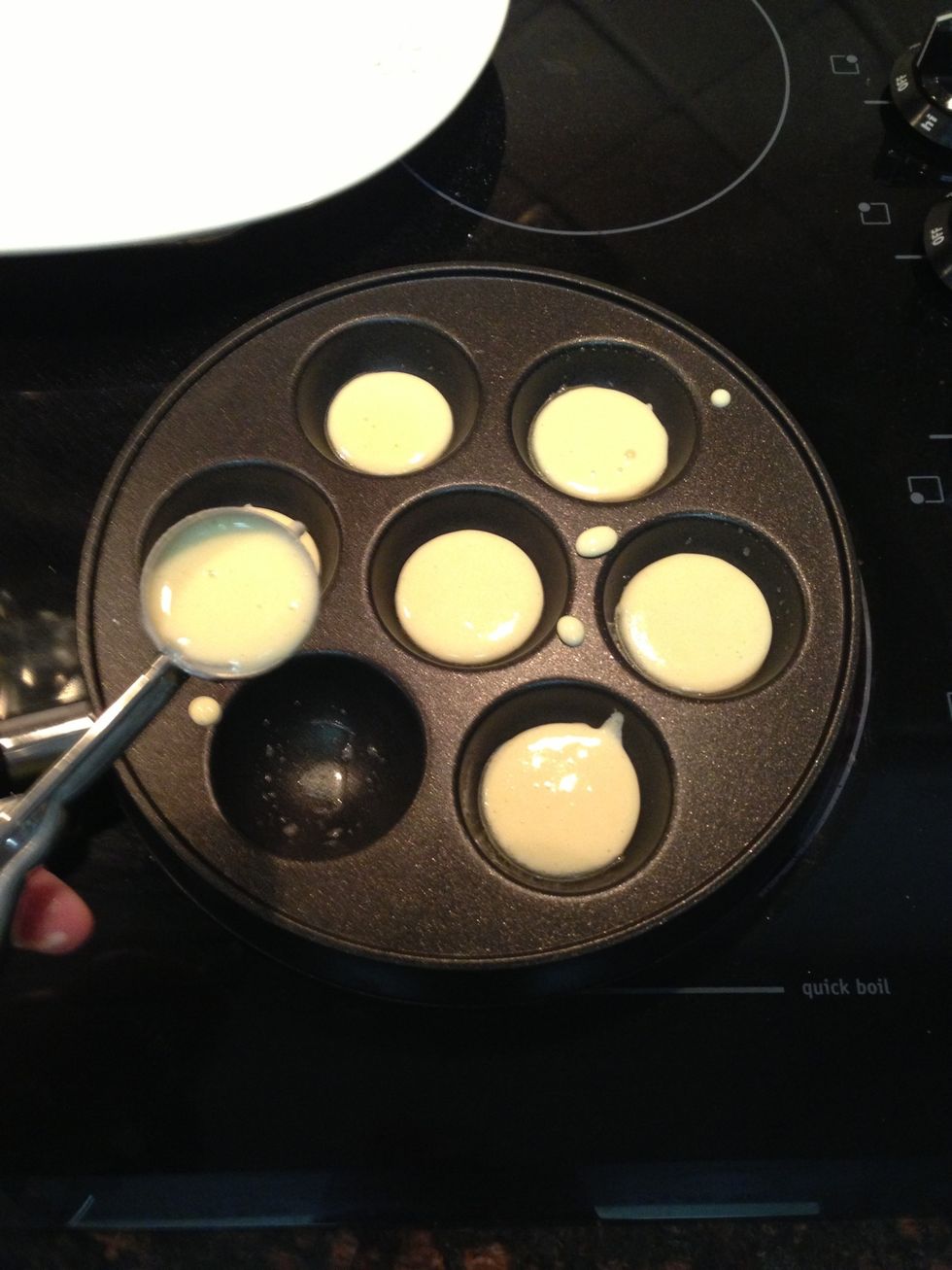 After brushing each well with butter, add 1 tsp of batter.