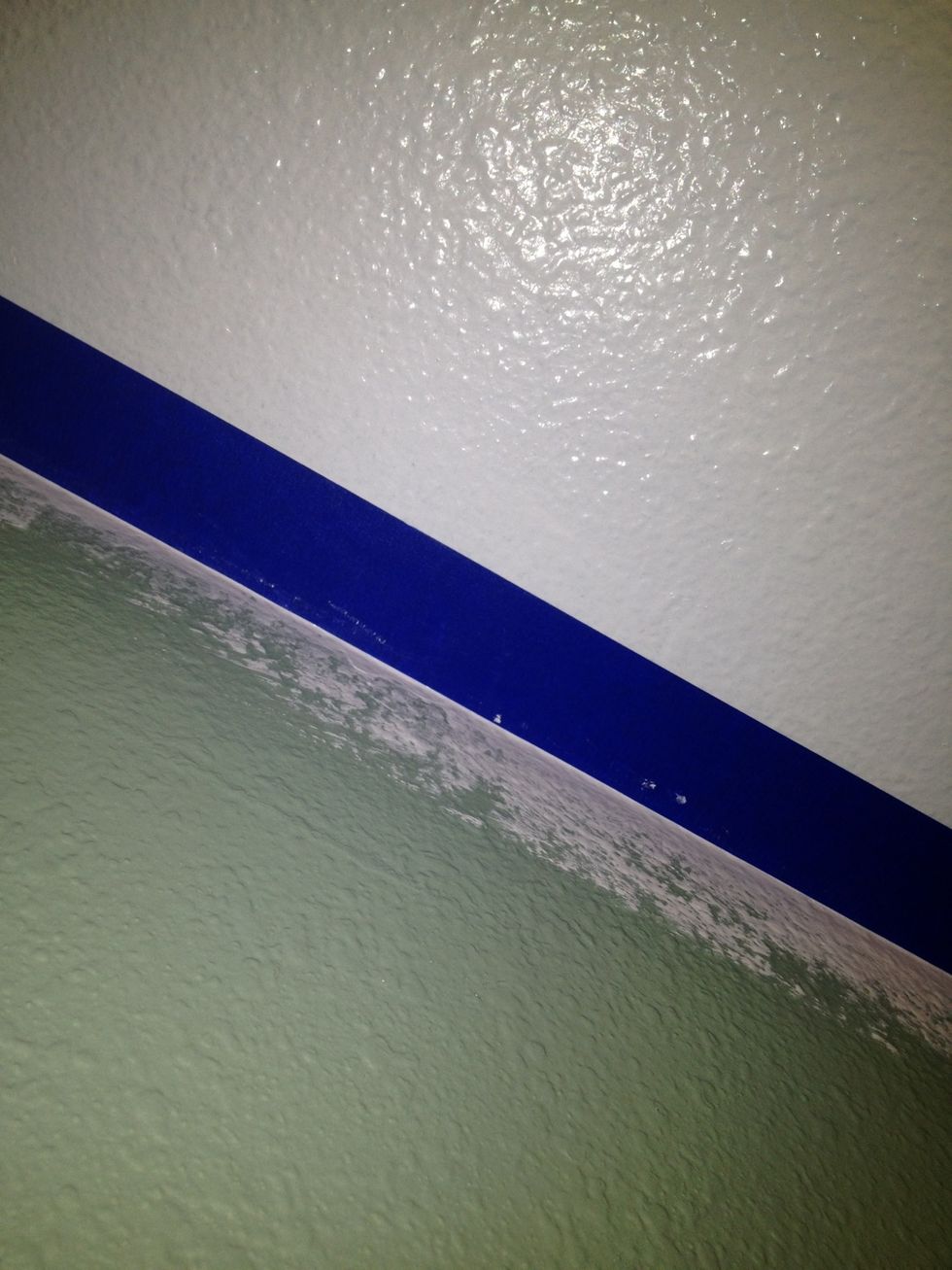 After ceiling or trim are painted and dry apply blue painters tape on the ceiling or trim in line with the wall. It is important that the paint is dry so the final step is successful.