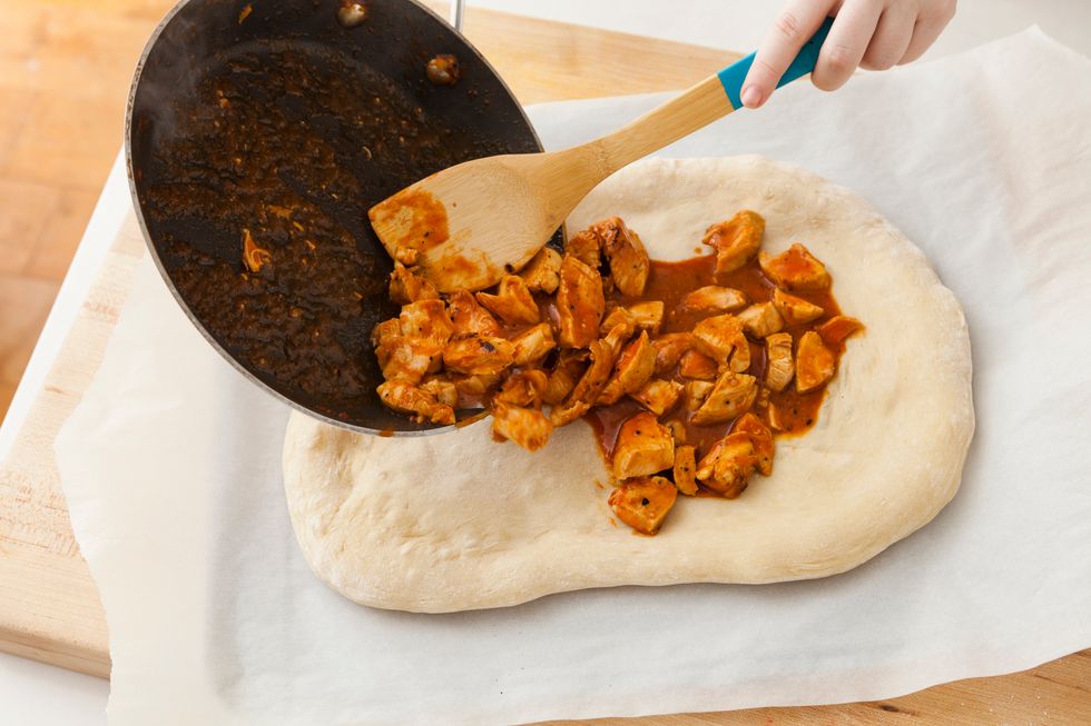 After cooking the crust for 5-10 minutes, pull out the crust and cover the dough with your buffalo chicken pieces and sauce.