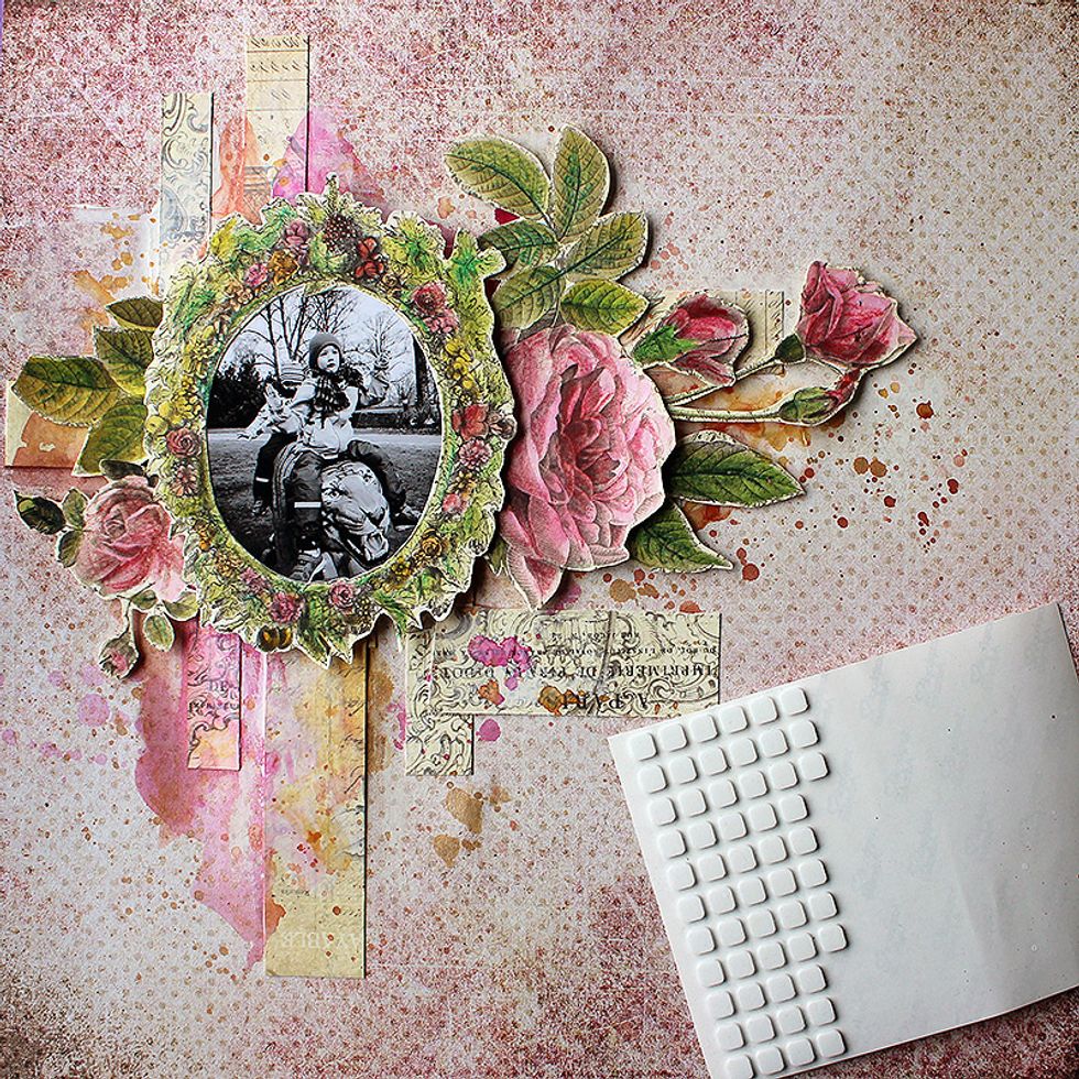 After drying start to build the layers. Attach the frame on top of your photo and use foam dots to adhere the frame and the flowers to the page. Make a cluster from the items.