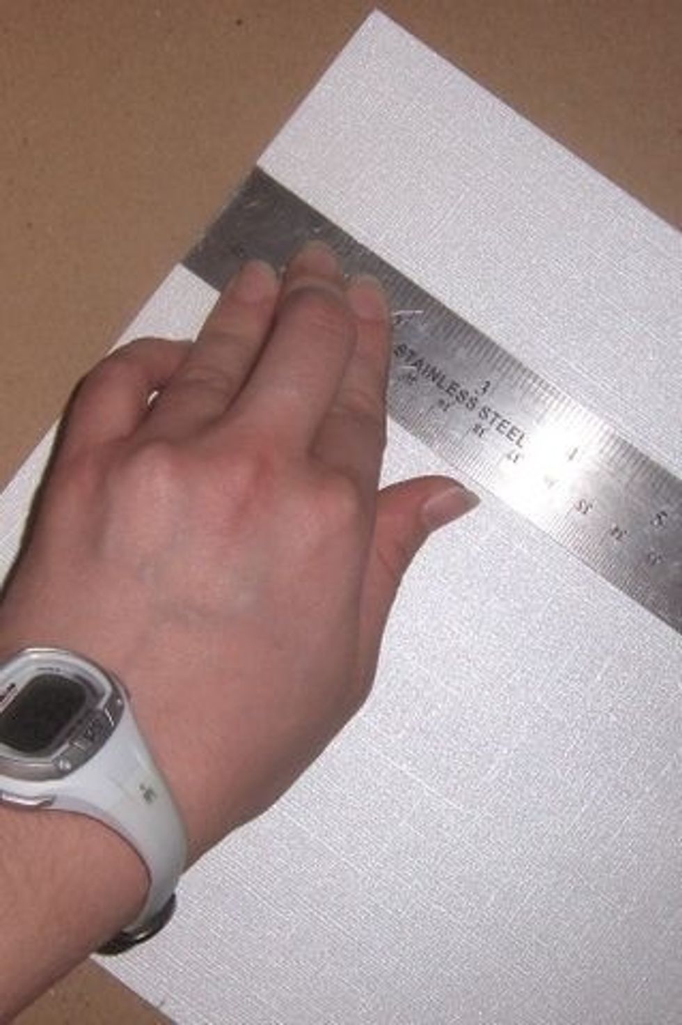 After folding your card stock in half, measure how much paper you want to line the inside with. Cut the liner paper to size with exacto knife against ruler; do this on a rubber mat or cardboard.