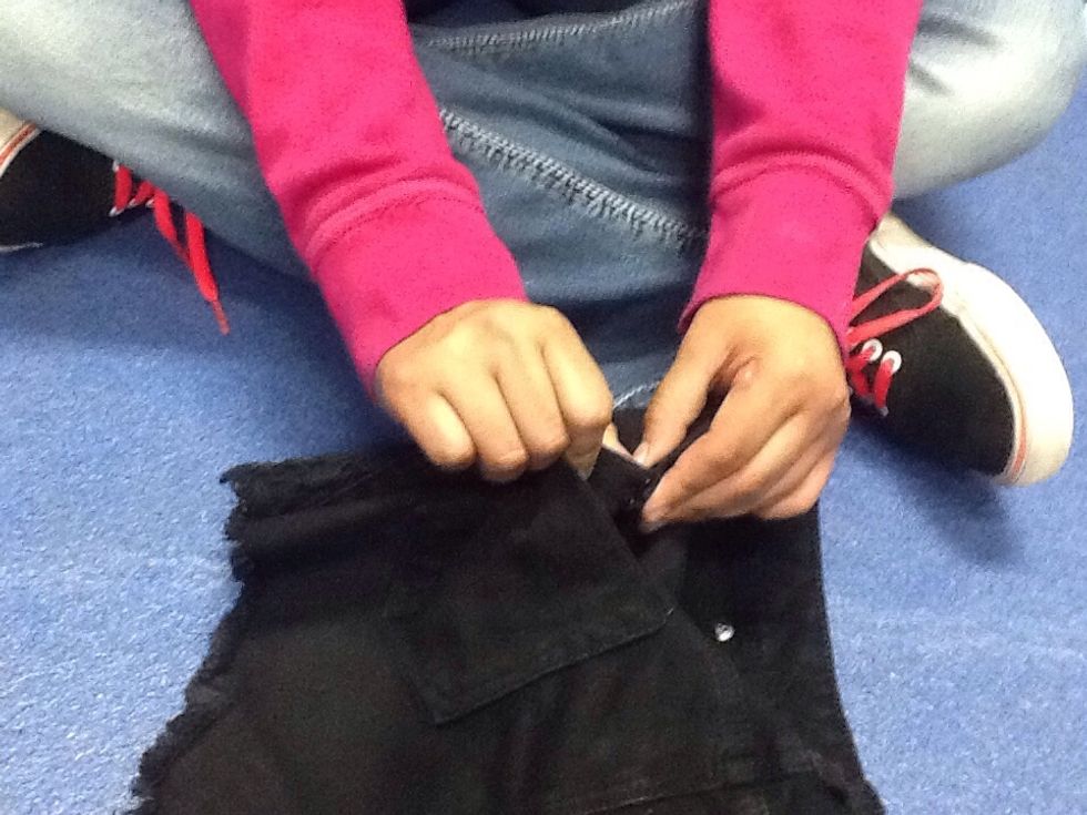 After letting the paint dry push the prongs into the part of the shorts you want to stud. Take something such as scissors and push the prongs down as to not stab yourself when you wear the shorts.