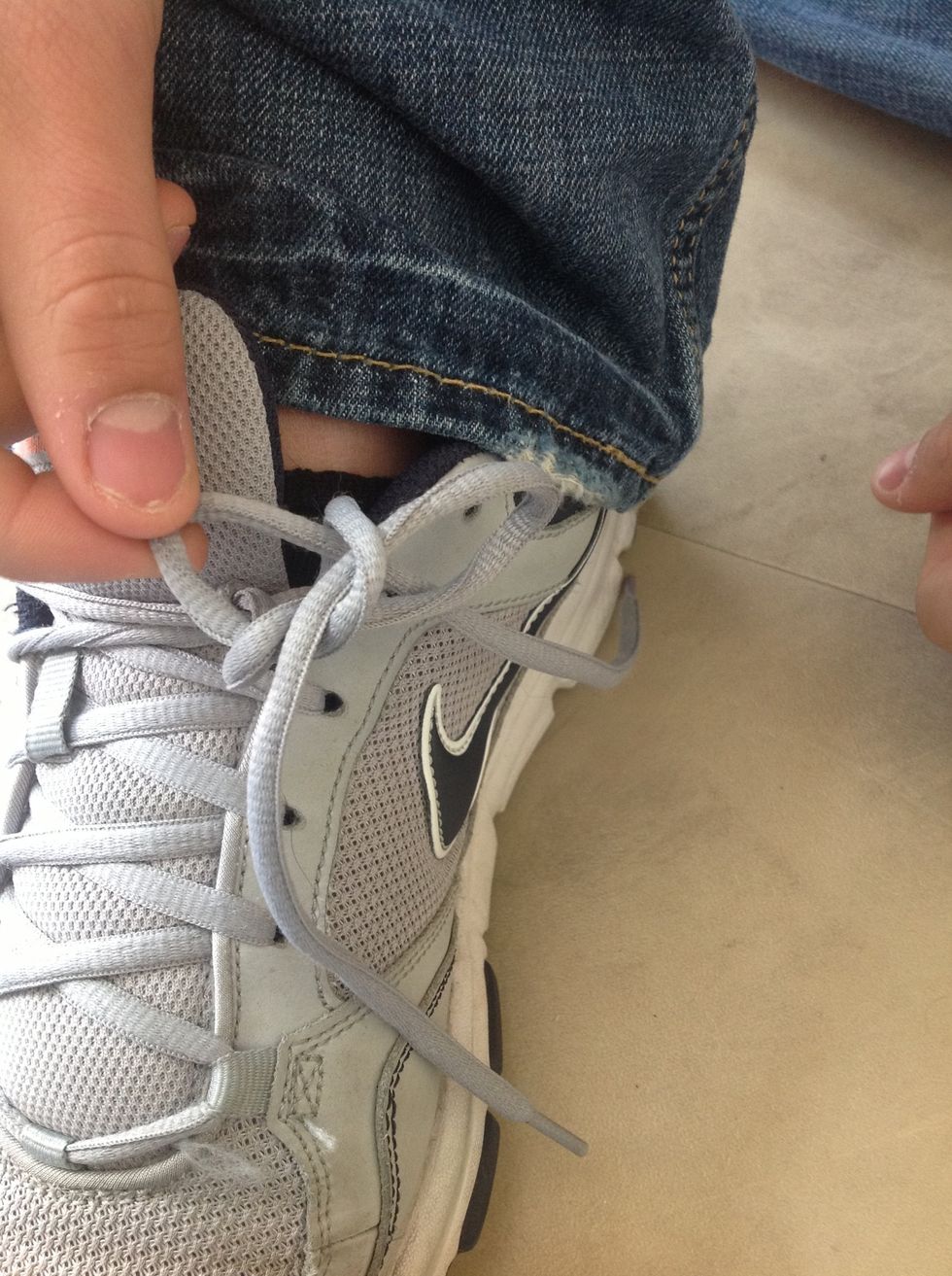 After looping it around, pull the middle of the string through the hole.