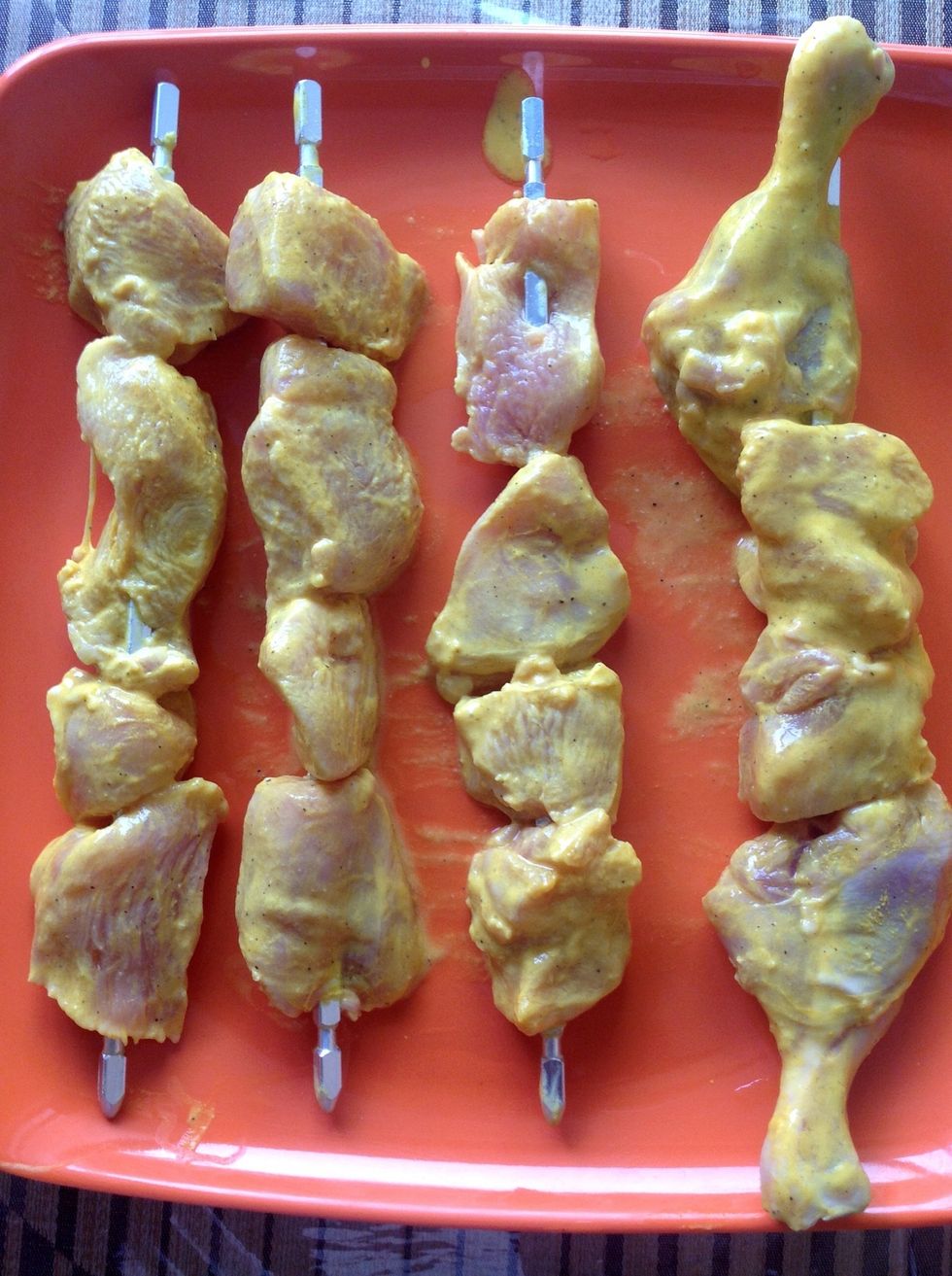 After marination, put the chicken pieces on the skewer rods.